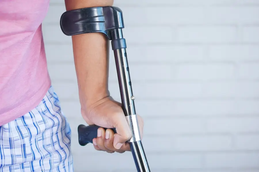 Arm stützt sich auf eine Unterarmgehstütze